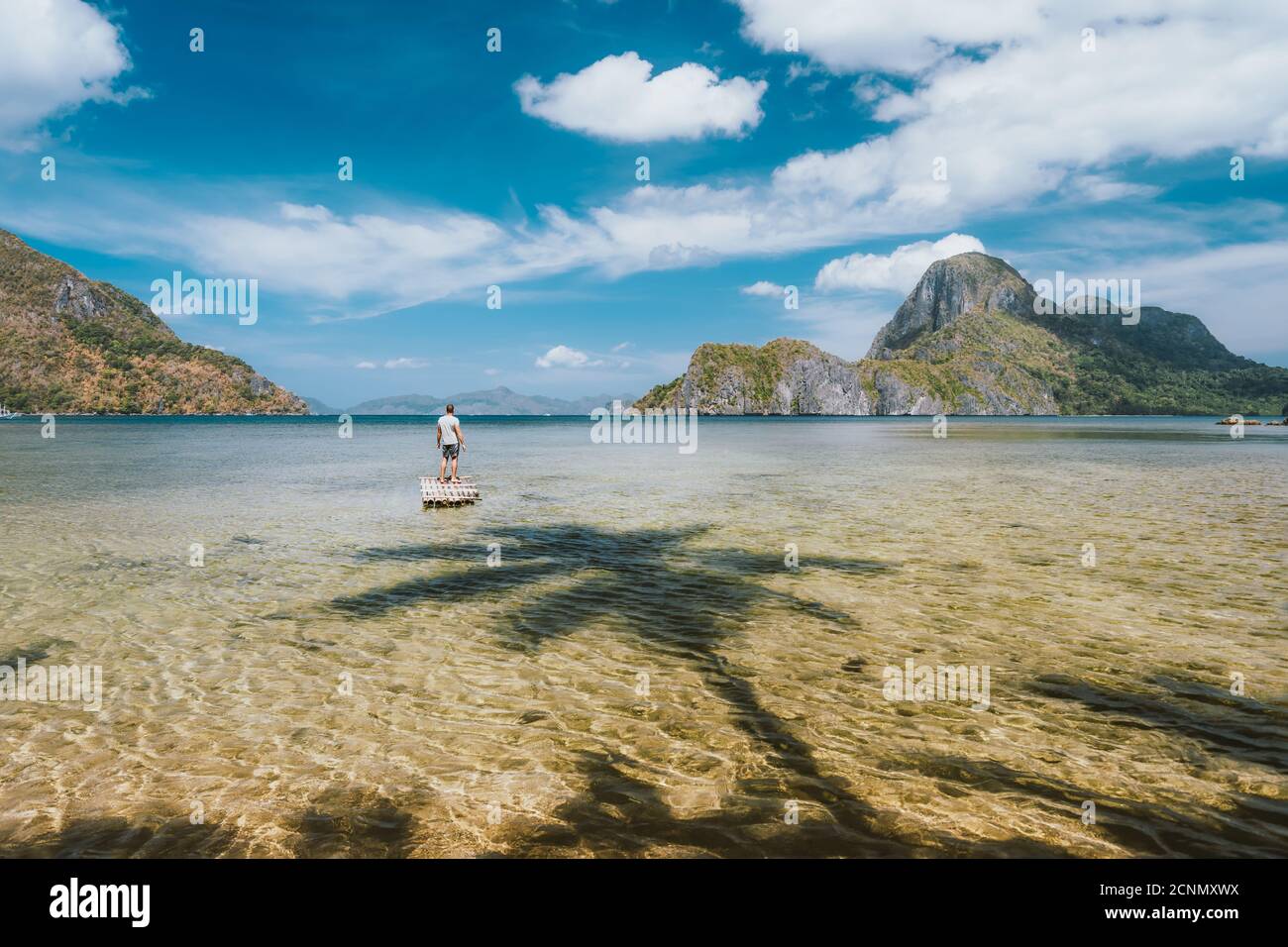 Man staying on bamboo float with impressive view of Cadlao island. Palawan, Philippines. Holiday vacation concept. Stock Photo