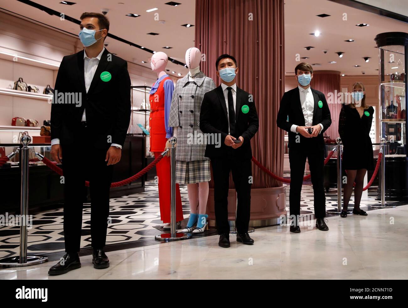 Staff members, wearing protective face masks, stand in front of a Gucci  shop inside the department store Le Printemps Haussmann before its  reopening in Paris as France eases gradually its lockdown measures