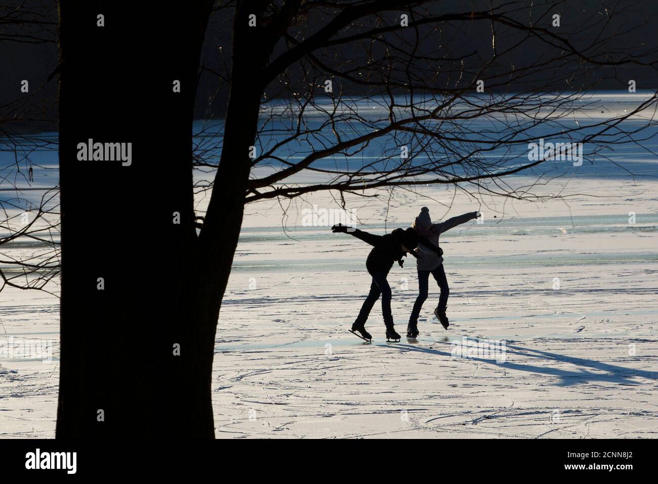A woman and a girl skate on a frozen lake on a cold sunny day in Berlin's Charlottenburg district, February 1, 2012. The cold snap which has gripped Europe and killed 60 people in the east is set to lift European power and gas prices further as energy demand for heating surges while temperatures are expected to stay below freezing point. German met office DWD expected the icy high pressure front from northern Russia to last well into next week. REUTERS/Thomas Peter (GERMANY - Tags: ENVIRONMENT SOCIETY) Stock Photo