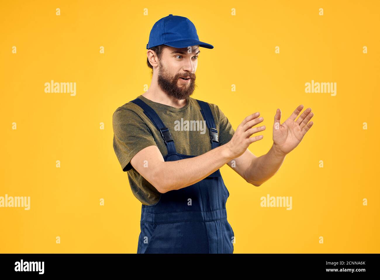 Worker man in uniform worker service yellow background emotion Stock