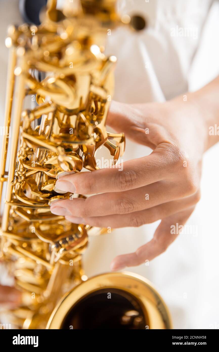 Close up woman playing saxophone isolated on white studio background. Inspired musician, details of art occupation, world classic instrument for jazz and blues. Concept of hobby, creativity. Stock Photo