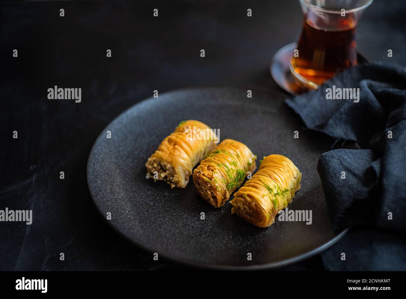 Three baklava desserts on a plate with black tea Stock Photo