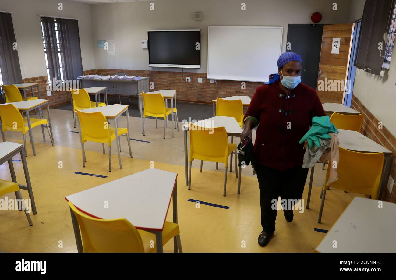 A worker walks past safely spaced desks following safe distancing measures amid the spread of the coronavirus disease (COVID-19) outbreak, at the Seshegong secondary school in Olivenhoutbosch, South Africa, May 28, 2020. REUTERS/Siphiwe Sibeko Stock Photo