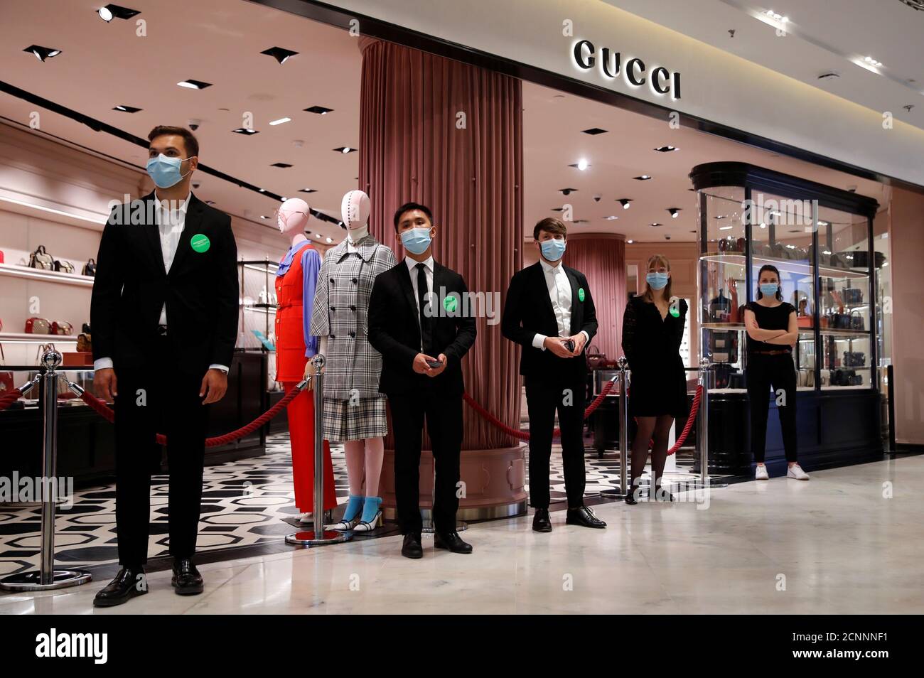 Staff members, wearing protective face masks, stand in front of a Gucci  shop inside the department store Le Printemps Haussmann before its  reopening in Paris as France eases gradually its lockdown measures