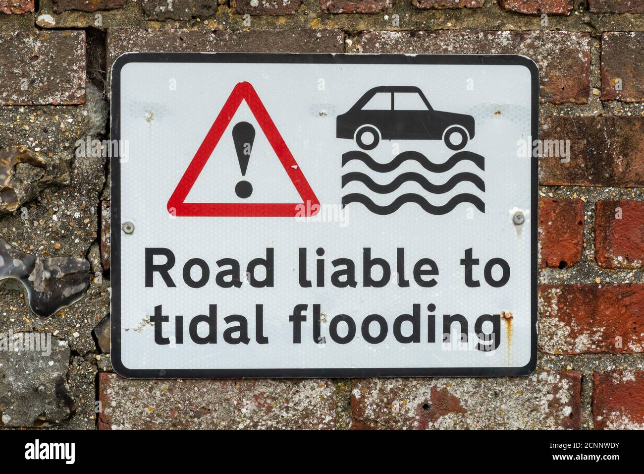 Warning sign on road by the sea reading Road liable to flooding Stock Photo