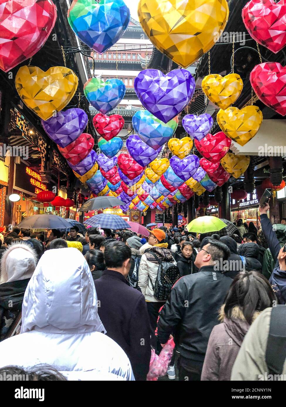 Heartshaped lanterns hung on the ceiling in a crowed places with shops