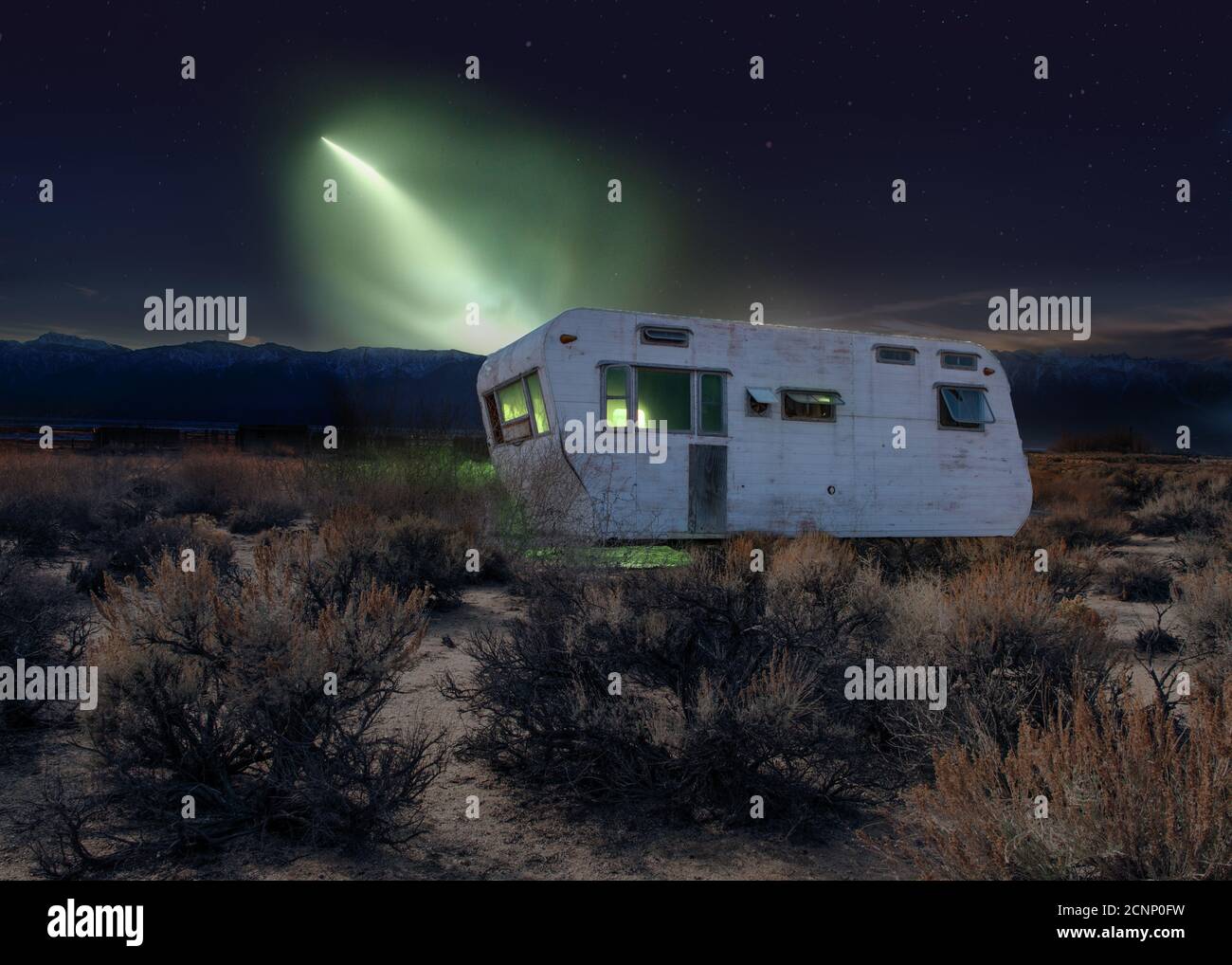 Mysterious light shining on an old abandoned caravan in the desert, USA Stock Photo