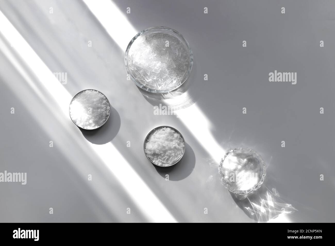 Ingredients for the production of cosmetics on a white background. Clays, wax, herbal powders, dried flowers, raspberry ketone, menthol crystals. Natural cosmetics concept. Stock Photo