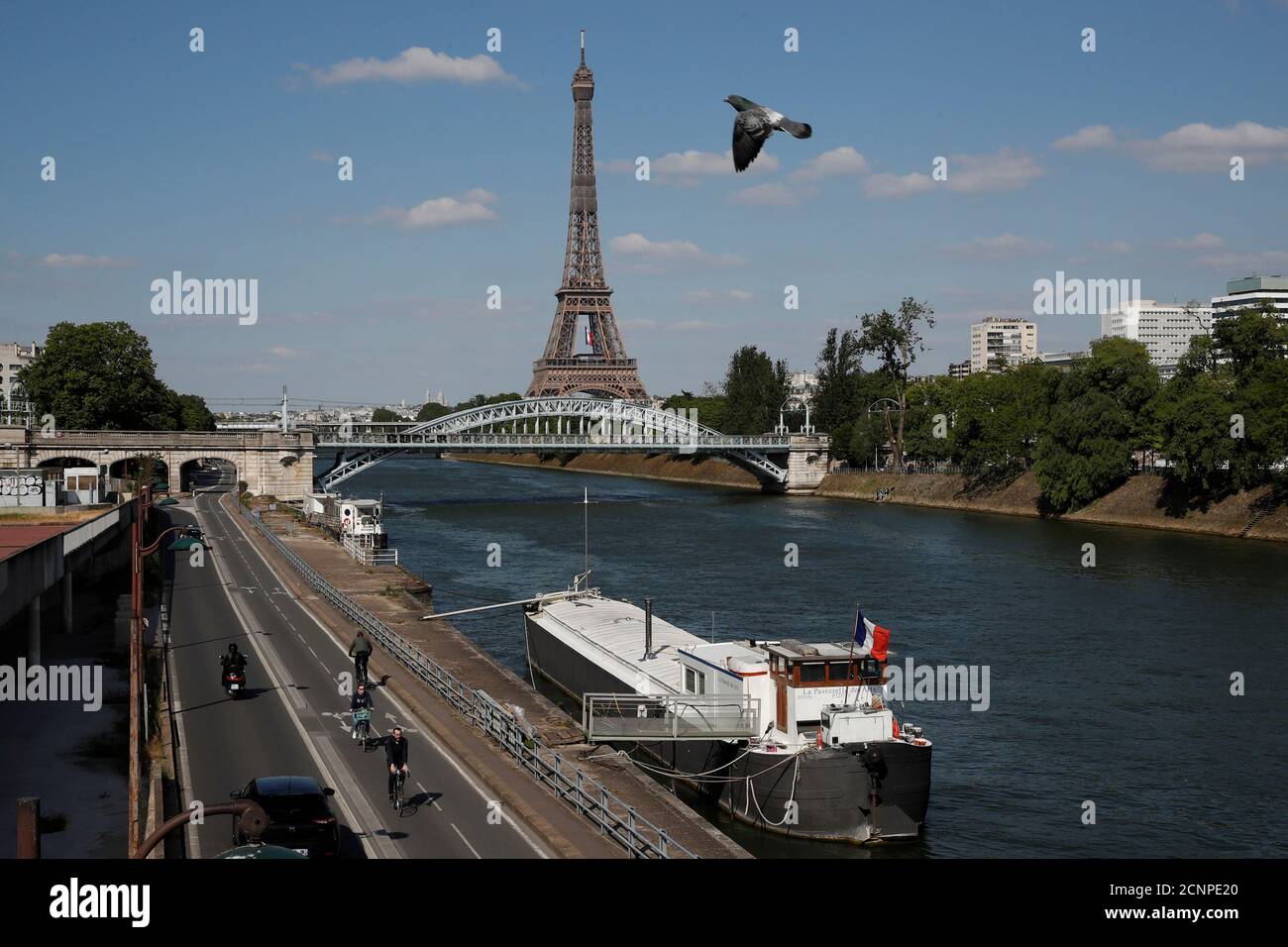 People ride bicycles on a bike path on the banks of the river Seine with the Pont Rouelle bridge and the Eiffel tower in the background in Paris during the outbreak coronavirus disease (COVID-19) in France, May 14, 2020. REUTERS/Gonzalo Fuentes Stock Photo