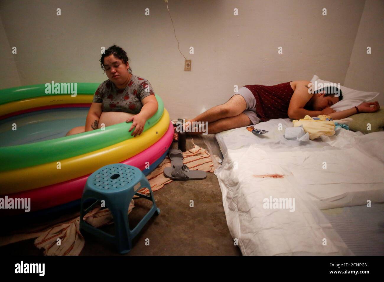 Miguel Flores Torres, 24, rests on a bed next to his wife Karla Lopez Rangel, 24, who is pregnant, as she sits in a inflatable birthing pool while labouring at their home, where she plans to give birth, during the coronavirus disease (COVID-19) outbreak, in Xochimilco, Mexico City, Mexico, May 25, 2020. REUTERS/Gustavo Graf     SEARCH 'COVID-19 MEXICO BIRTH' FOR THIS STORY. SEARCH 'WIDER IMAGE' FOR ALL STORIES. Stock Photo