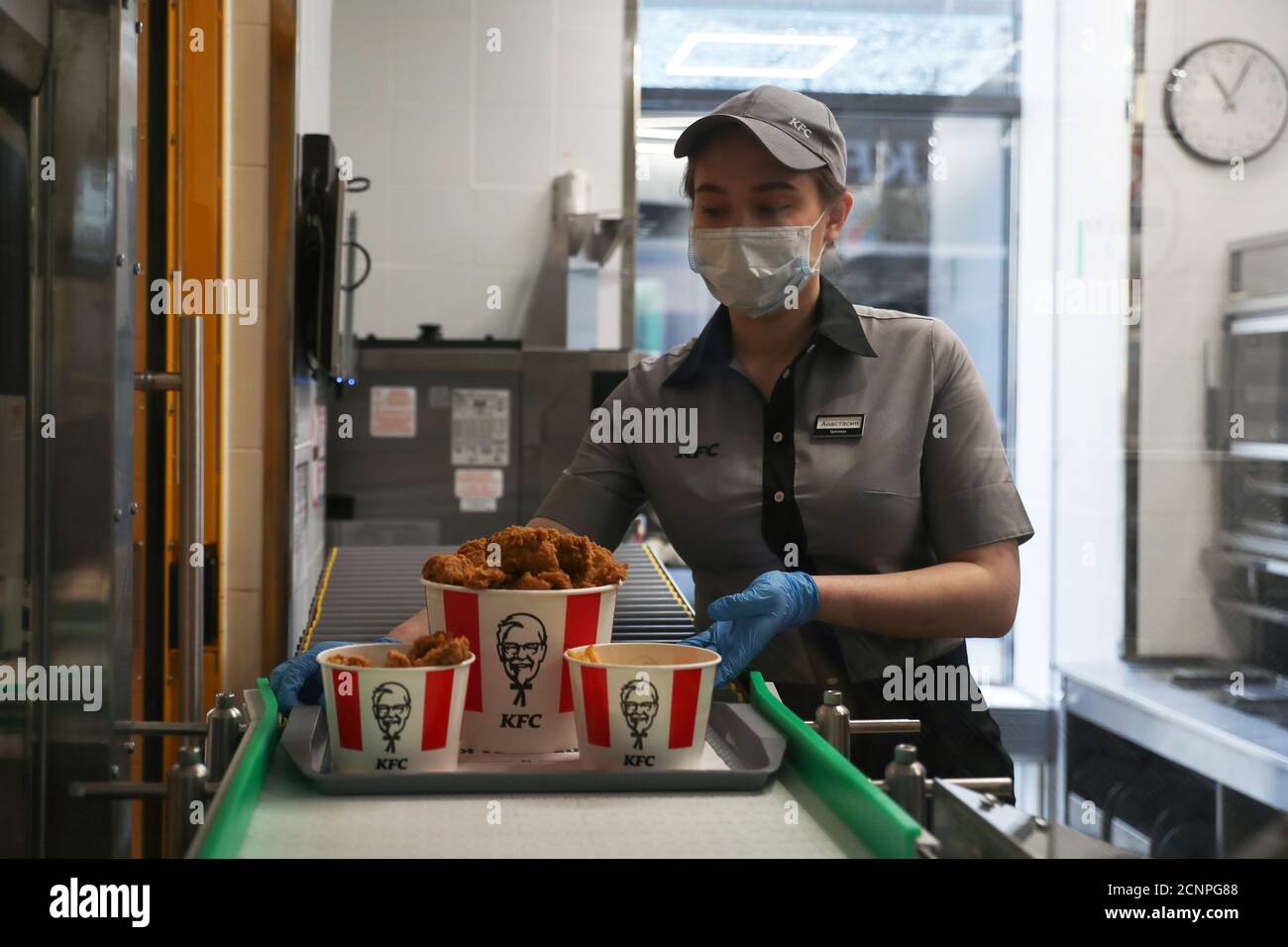 An employee places a tray of food to a conveyor belt at a KFC restaurant offering contactless service, ahead of its opening following the easing of restrictions implemented to curb the spread of the coronavirus disease (COVID-19) in Moscow, Russia June 21, 2020. REUTERS/Evgenia Novozhenina Stock Photo