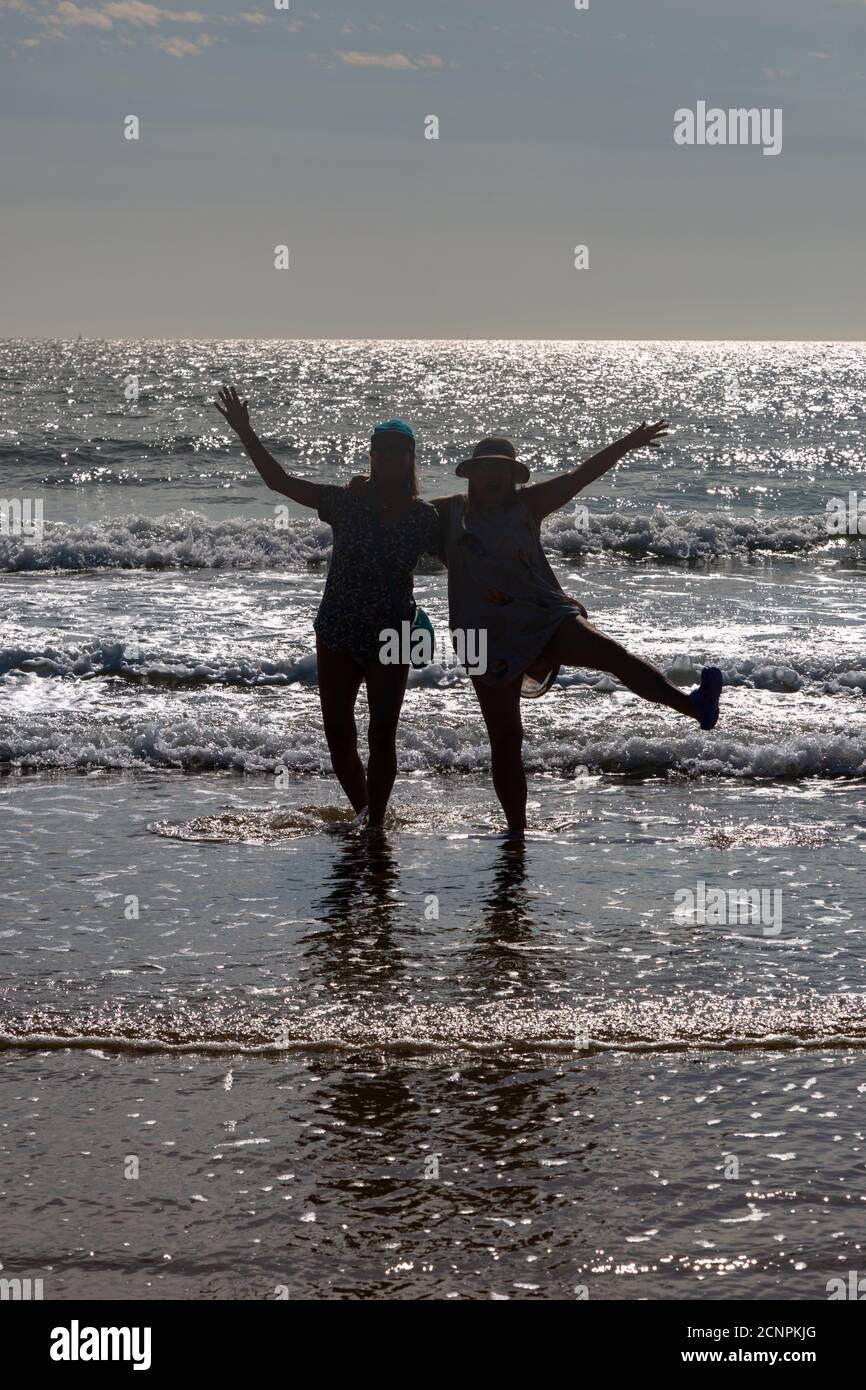 Silhouette of two women having fun on the beach, UK Stock Photo
