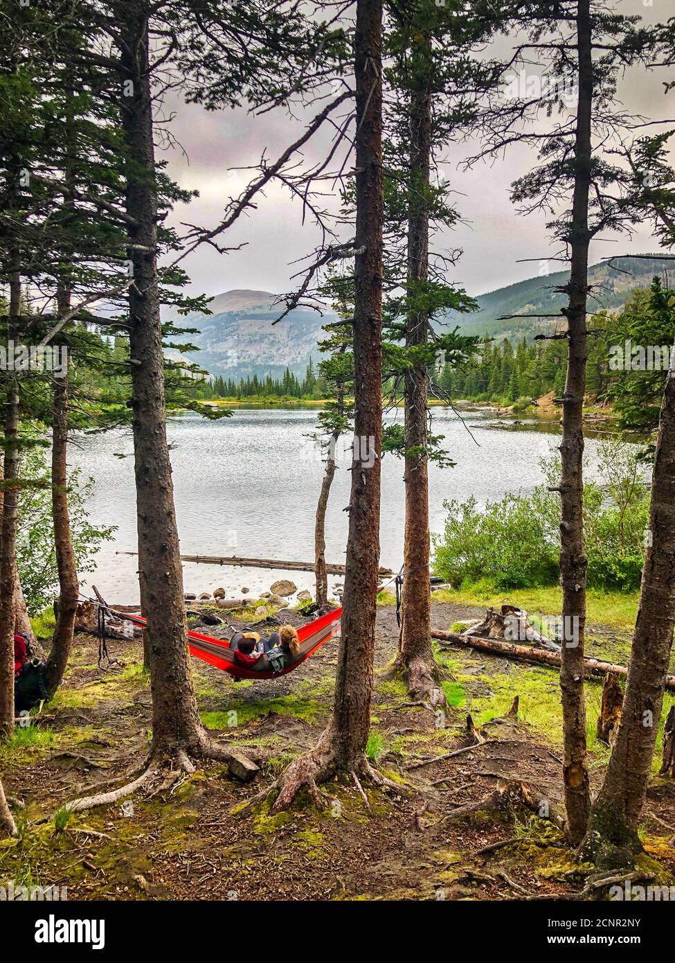 Couple resting on a hammock in a wooded area at Lost Lake Trail, a favorite local retreat area near Boulder, Colorado Stock Photo