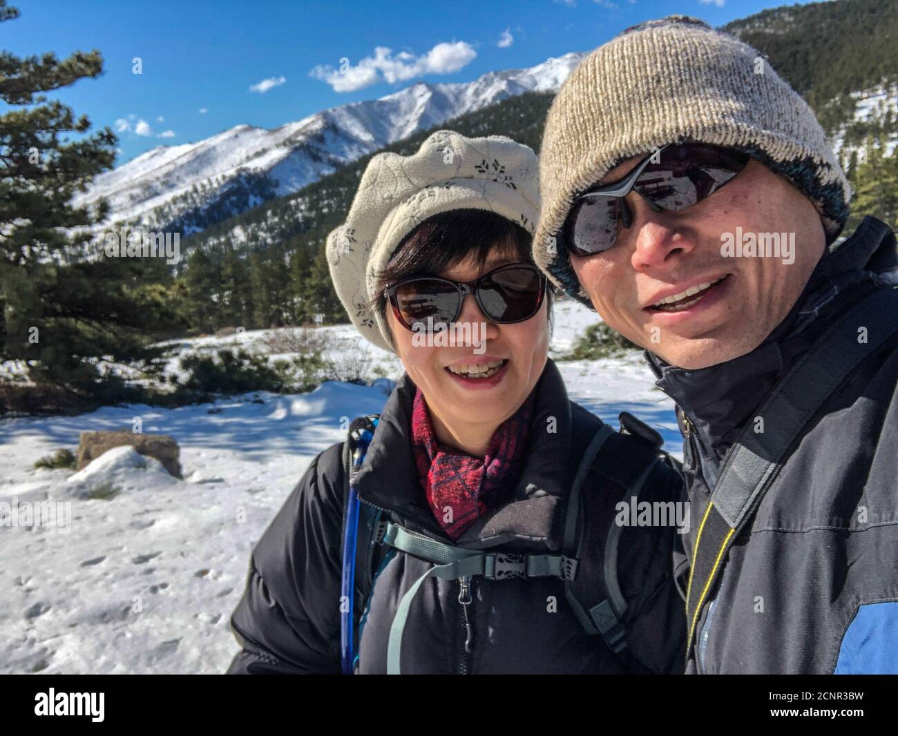 Asian couple in a white snowy mountain background, taking a local retreat nearby Boulder, Colorado. Stock Photo