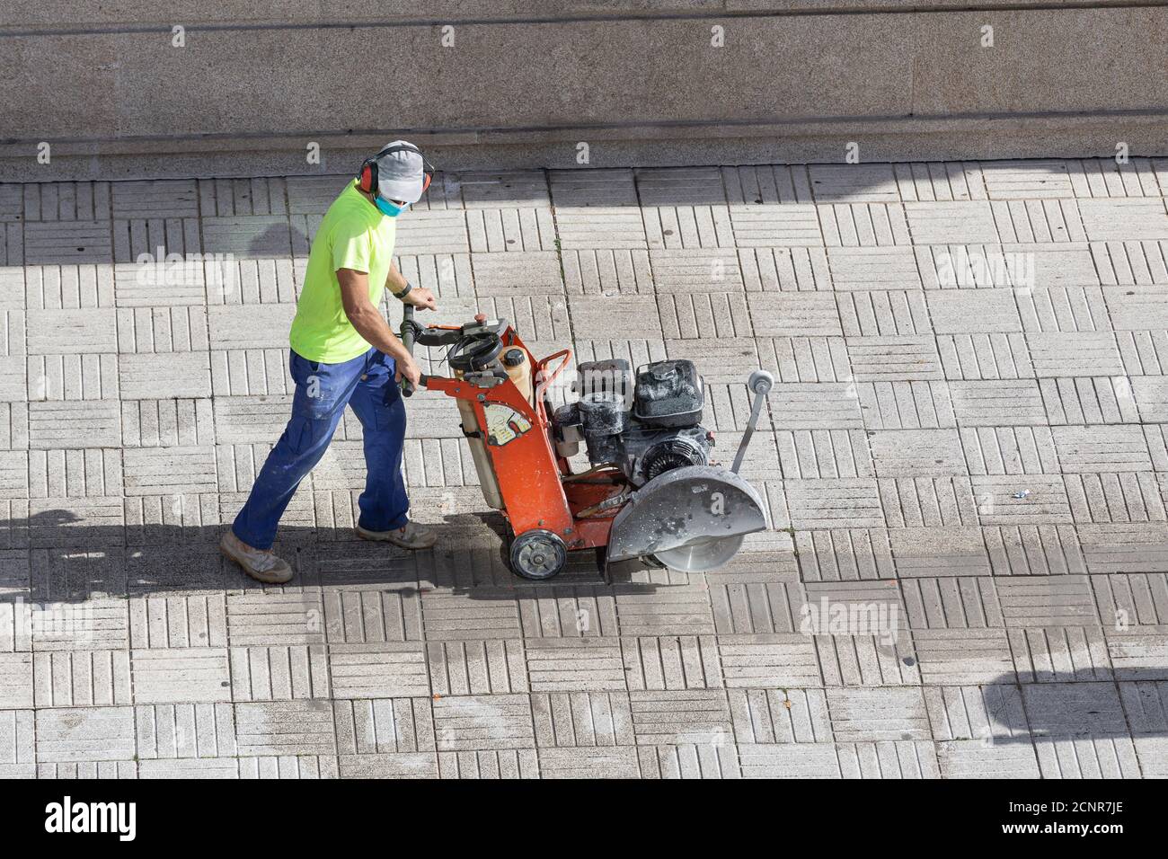Construction worker cutting paving stone floor with diamond saw blade machine on a sidewalk Stock Photo