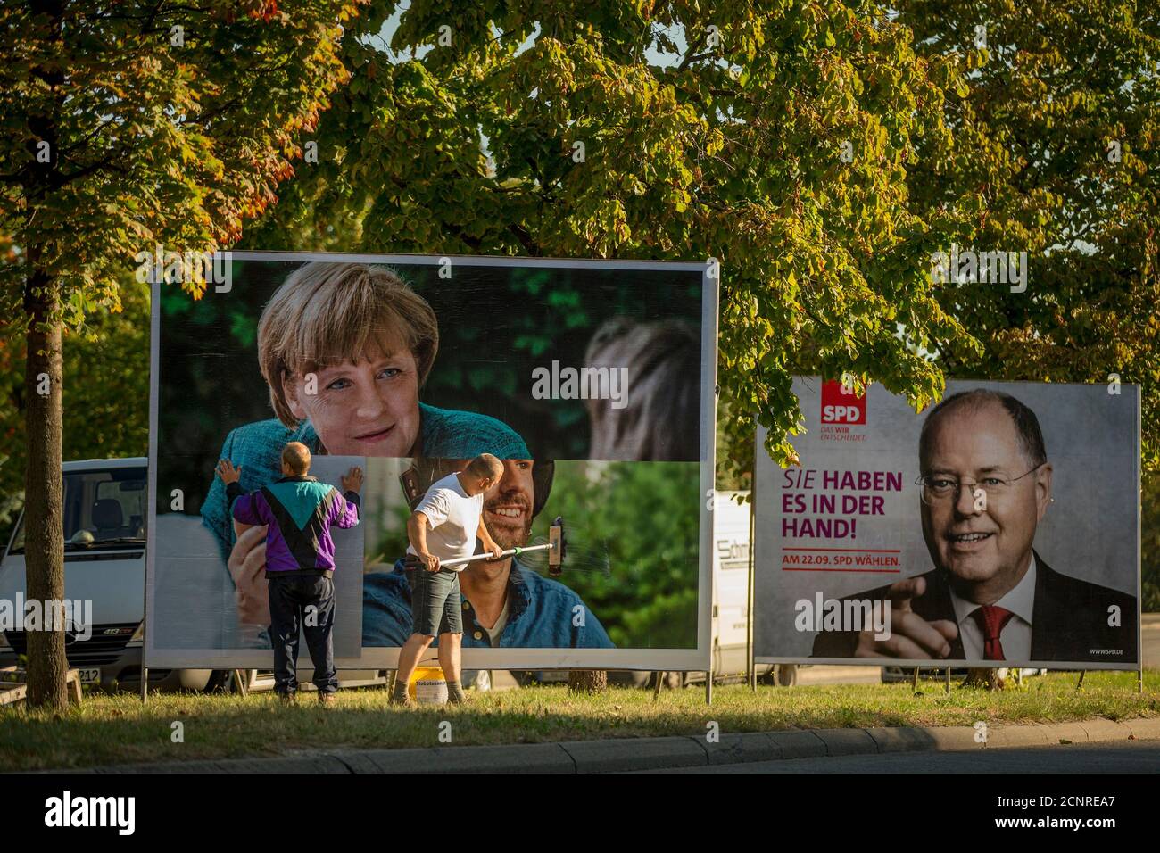 Workers paste up an election poster showing the top candidate of the Christian Democratic Union (CDU) in the upcoming German general elections, German Chancellor Angela Merkel, in Berlin, August 26, 2013. Pictured to the right is an election poster showing the top candidate of the Social Democratic Party (SPD) Peer Steinbrueck. German voters will take to the polls in a general election on September 22.  REUTERS/Thomas Peter (GERMANY  - Tags: POLITICS ELECTIONS) Stock Photo