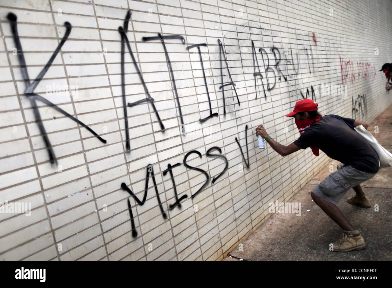 A member of Brazil's Landless Rural Workers' Movement spraypaints a graffiti message against Brazil's Agriculture Minister Katia Abreu during a demonstration against the fiscal adjustment and budget cuts proposed by the government in Brasilia, Brazil, September 23, 2015. REUTERS/Ueslei Marcelino Stock Photo
