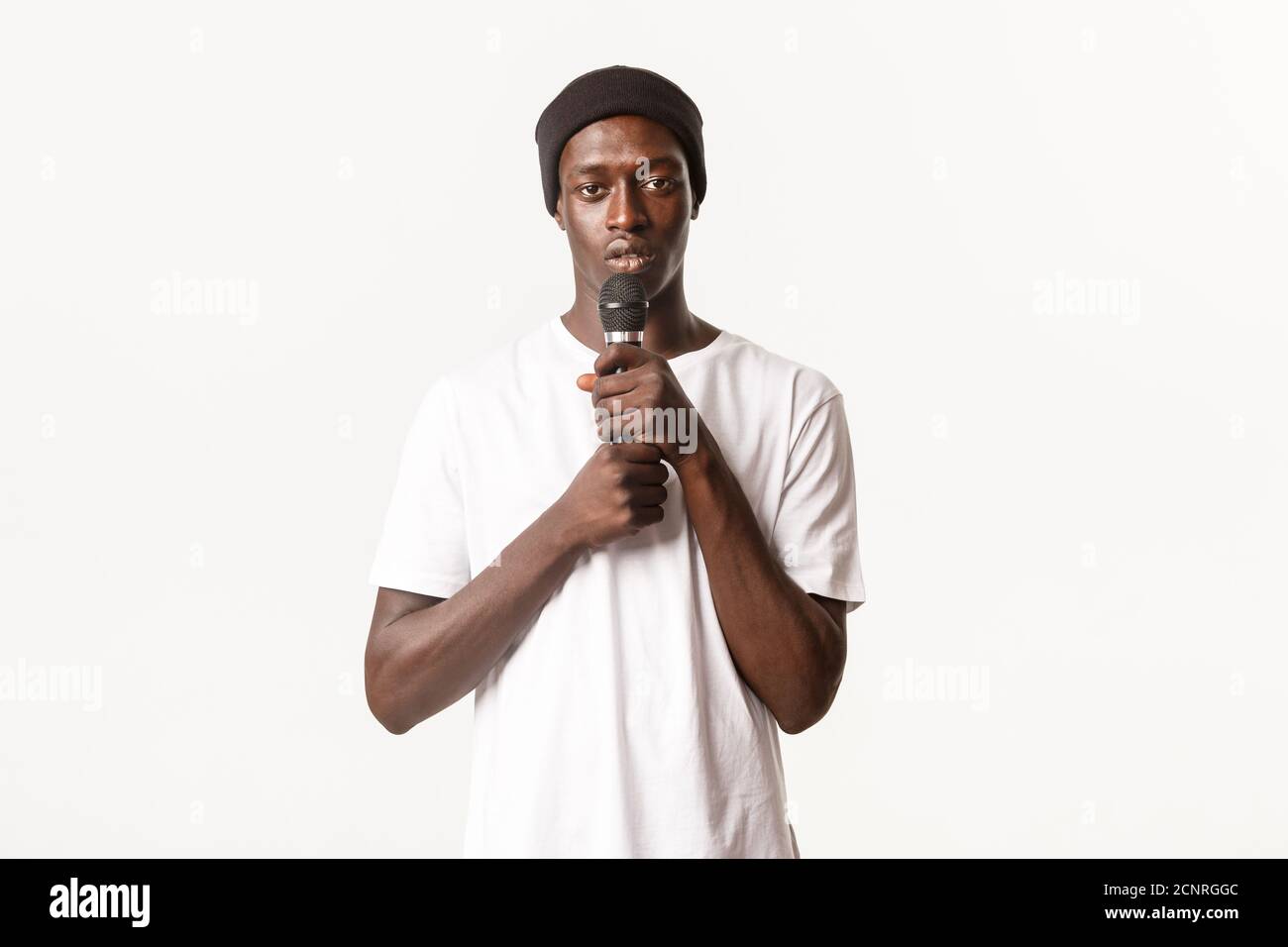 Portrait of young african-american guy performing song, holding microphone and singing karaoke, white background Stock Photo