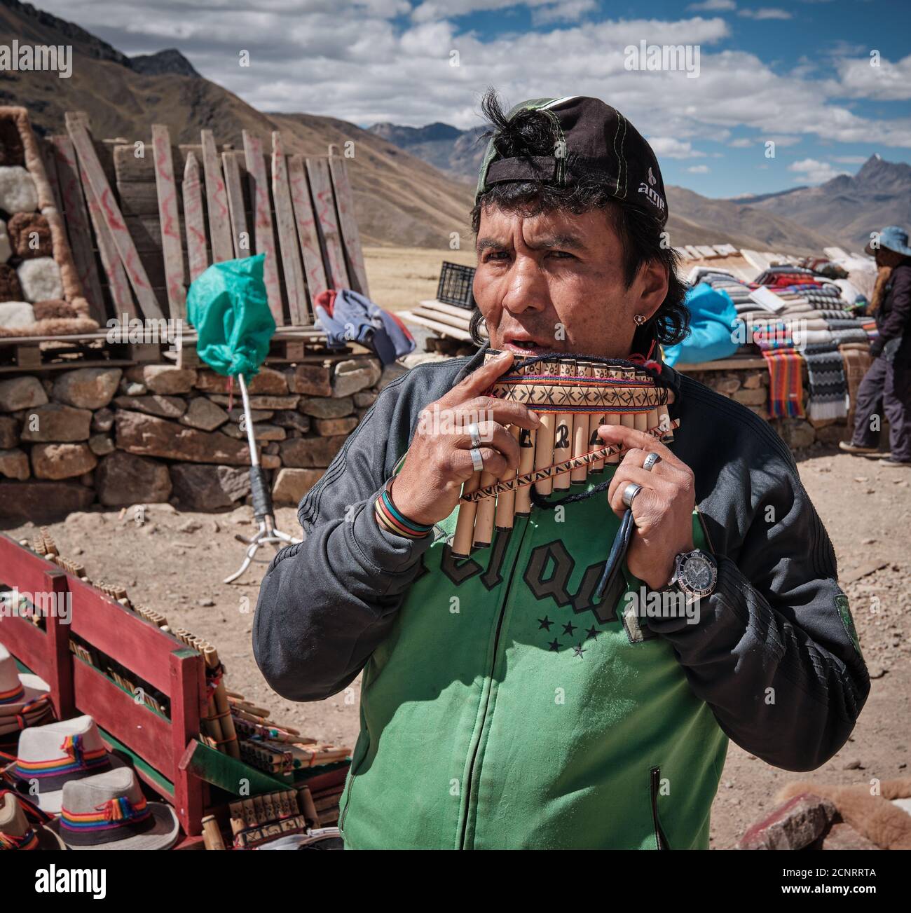 A market trader demonstrating pan pipes panpipes pan-pipes syrinx at a roadside market in the Altiplano high Andes, Peru, selling textiles and fabrics Stock Photo