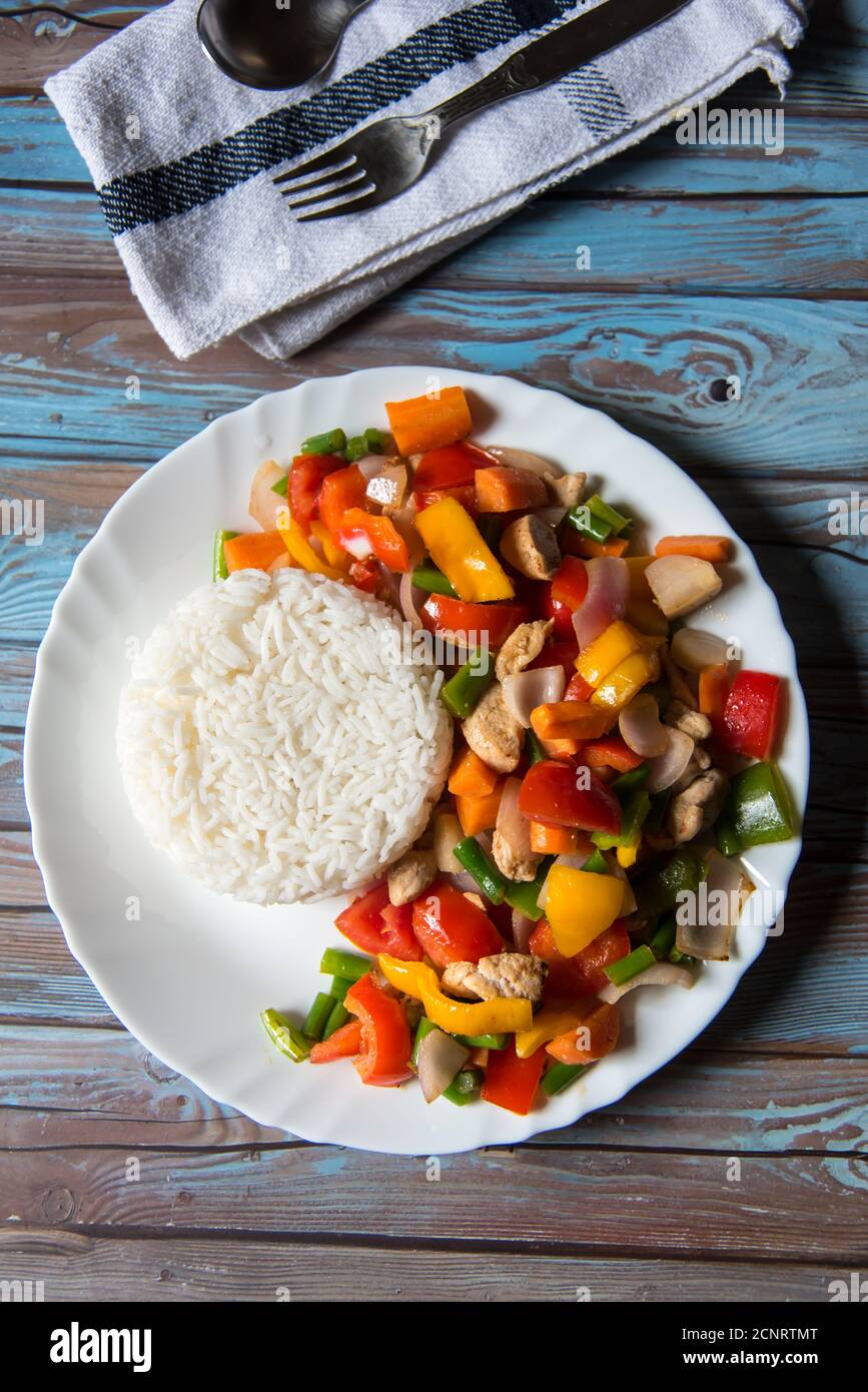 Steamed rice along with chicken and vegetables saute in a white plate on a background Stock Photo