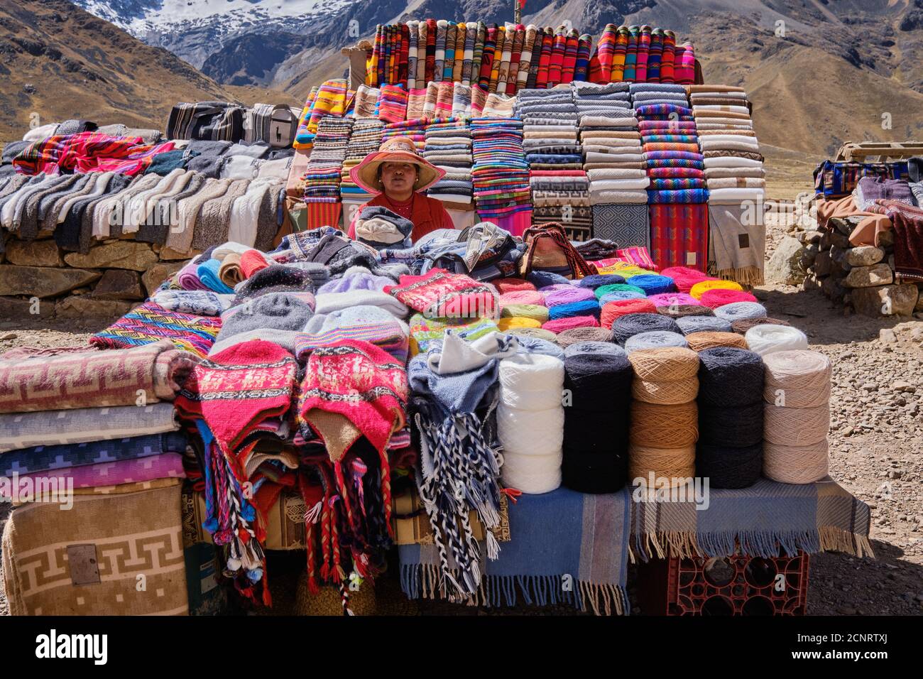 A roadside market in the Altiplano high Andes, Peru, selling textiles and fabrics, clothes and tourist souvenirs Stock Photo