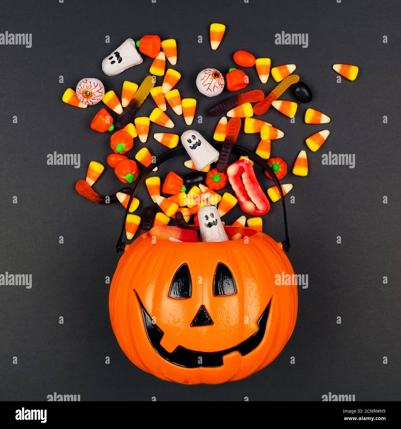 Halloween Jack o Lantern pail with spilling candy, top view on a black