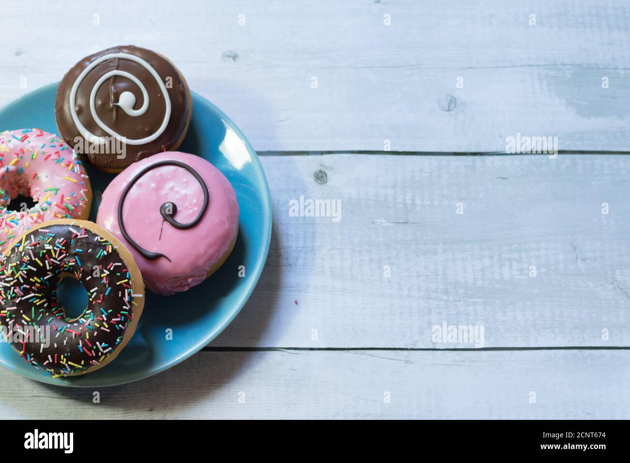top view of a plate of donuts on a blue plate on a wooden table Stock Photo
