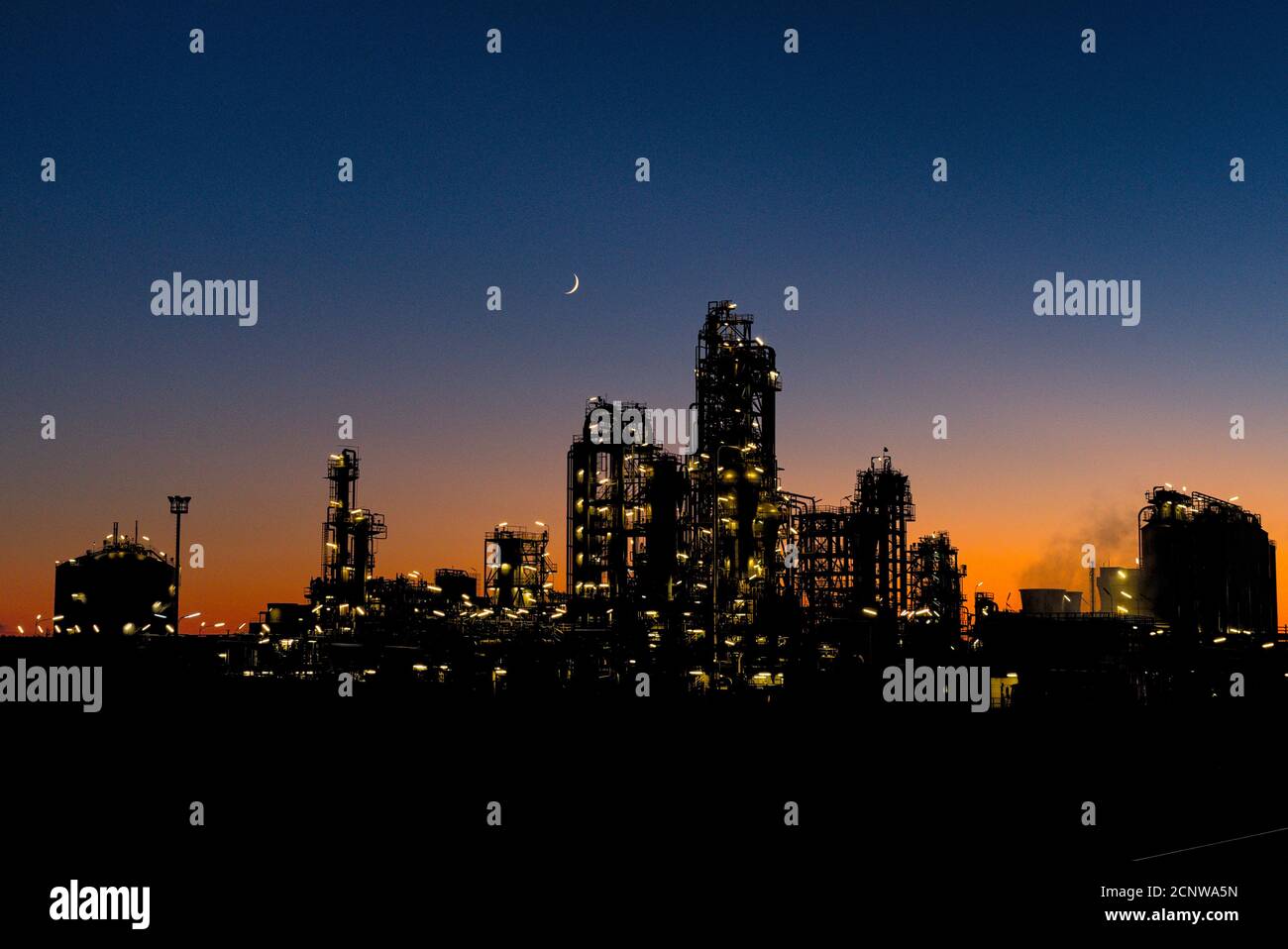 Industrianlage bei Sonnenuntergang mit Mondsichel Stock Photo