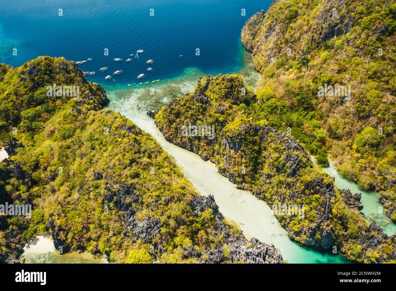 Palawan, Philippines aerial view of tropical Miniloc island. Tourism trip boats moored at entrance to big lagoon. Stock Photo