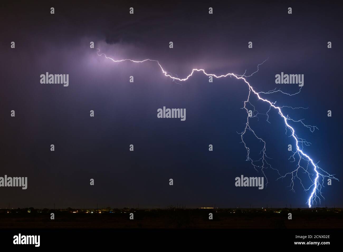 Stormy weather with a dramatic thunderstorm lightning strike in the night sky over Queen Creek, Arizona Stock Photo