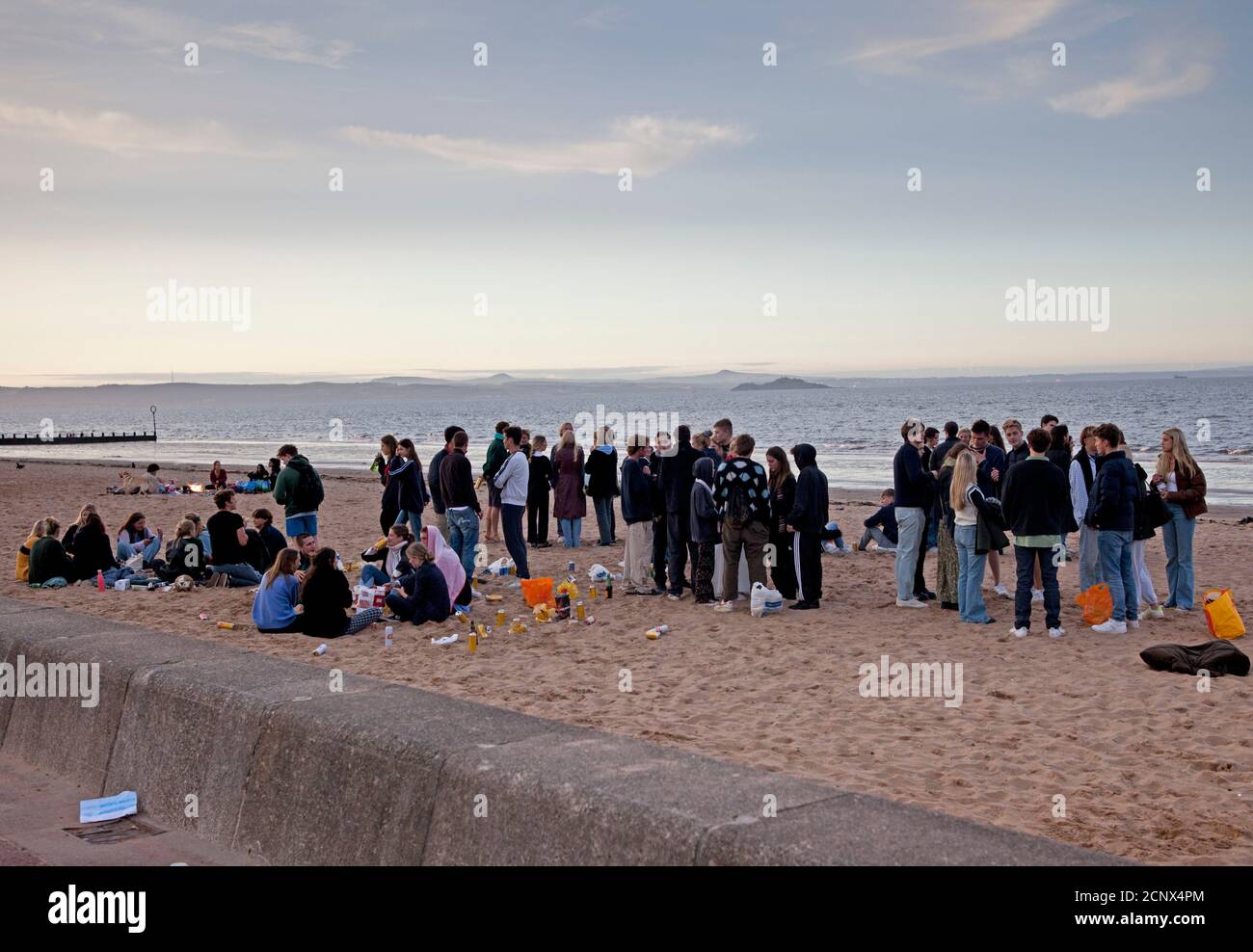 Portobello Beach, Edinburgh, Scotland, UK. 18 September 2020. Temperature 15 degrees. Evening at Portobello Beach after a busy day at the seaside things quitened off once the hazy sun was going down, a few students cycle towards the prom, one very smoky barbeque and two Irish lassies who work in Edinburgh exit from a bracing evening dip in the Firth of Forth. Credit: Scottishcreative/ Alamy Live News. Stock Photo