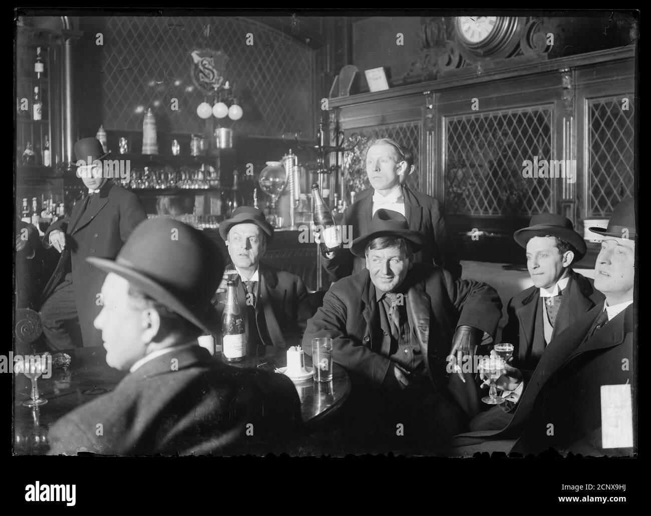 Saloon interior showing the bar, five men sitting around a table
