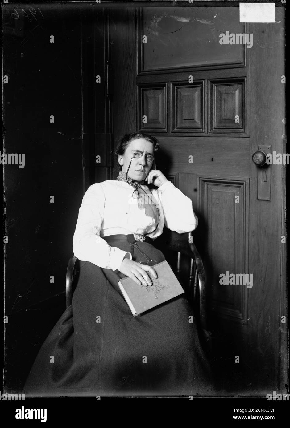 Three-quarter length portrait of Emma Goldman, sitting in a chair and facing the camera, in a room in Chicago, Illinois. Stock Photo
