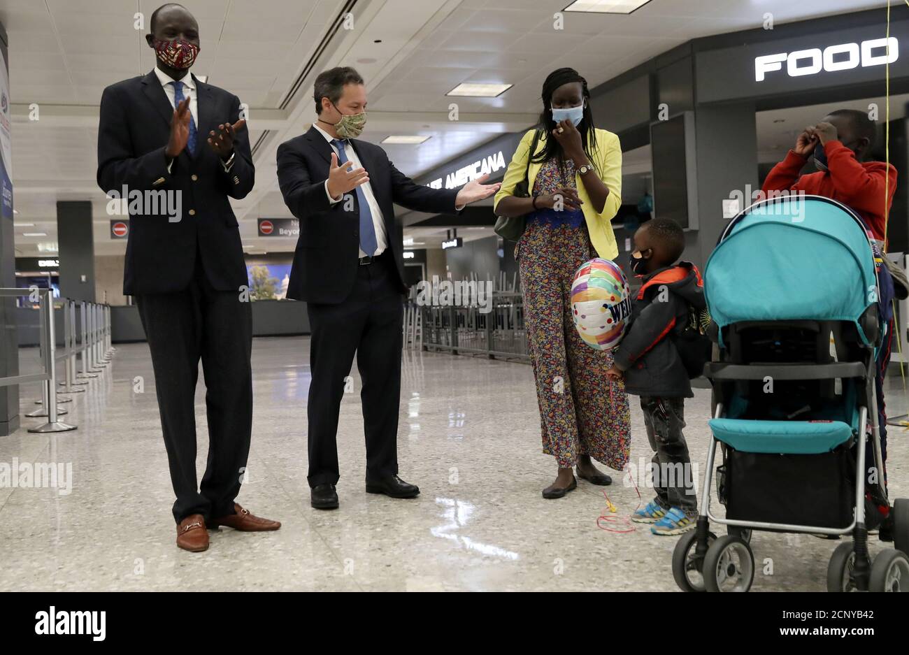 South Sudanese economist Peter Biar Ajak, his wife Nyathon Hoth Mai, and  their children Deng Biar, 7, (far R), Baraka Biar Ajak, 3, (C) and Isabelle  Biar Ajak, (in stroller), are greeted