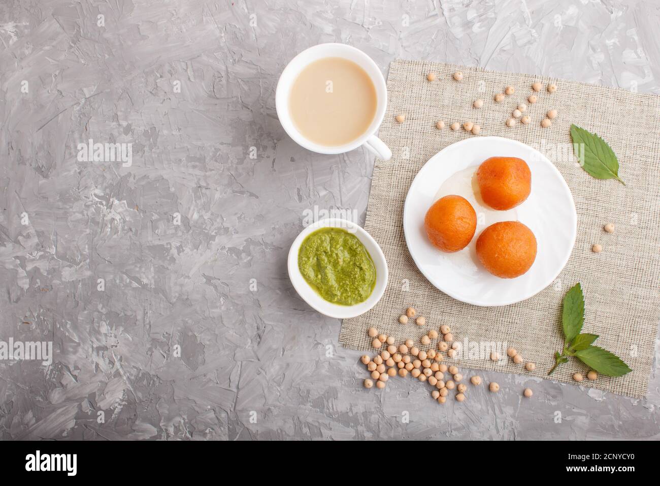 traditional indian candy gulab jamun in white plate with mint chutney