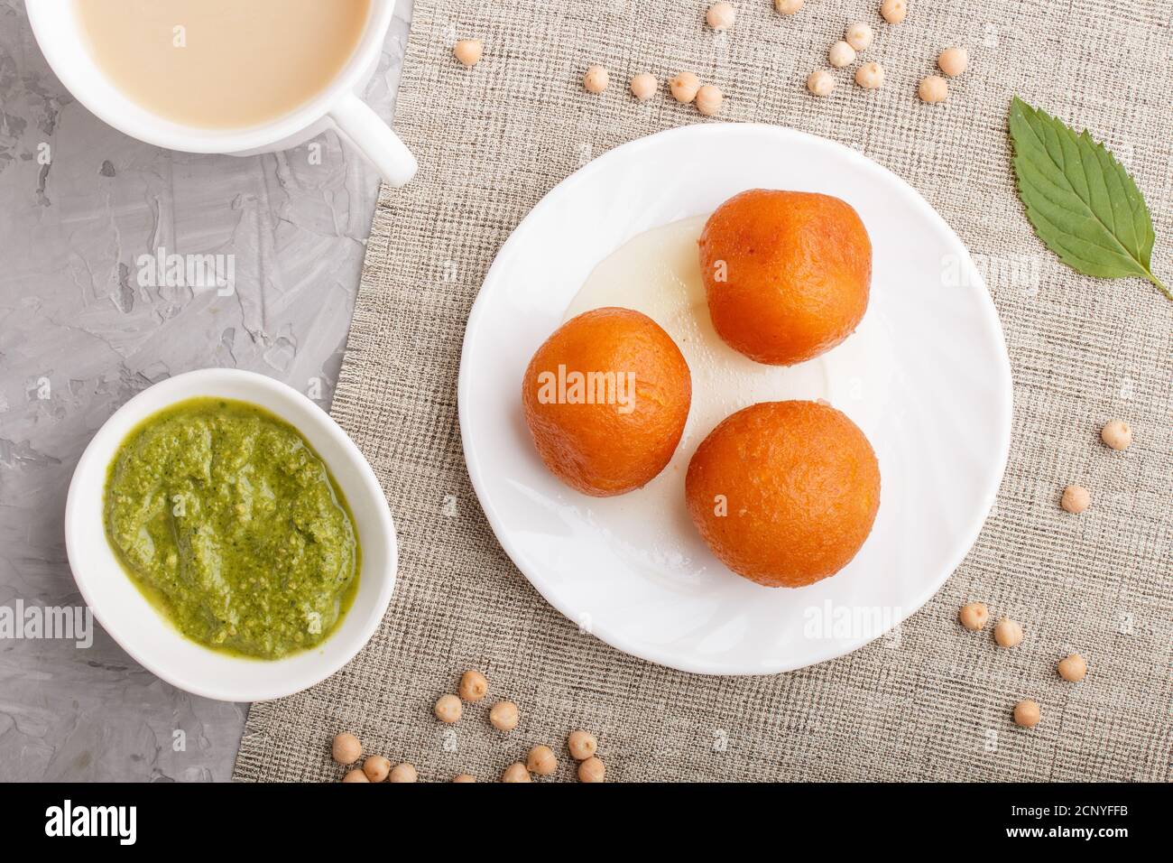 traditional indian candy gulab jamun in white plate with mint chutney