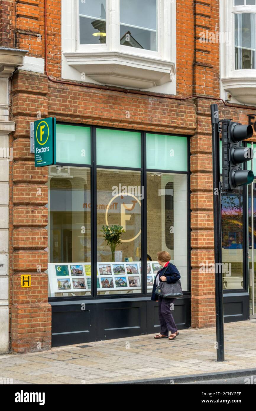 Woman glancing in window of Foxton's estate agents as she walks past. In Bromley, Kent. Stock Photo