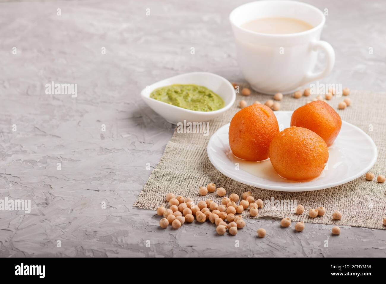 traditional indian candy gulab jamun in white plate with mint chutney