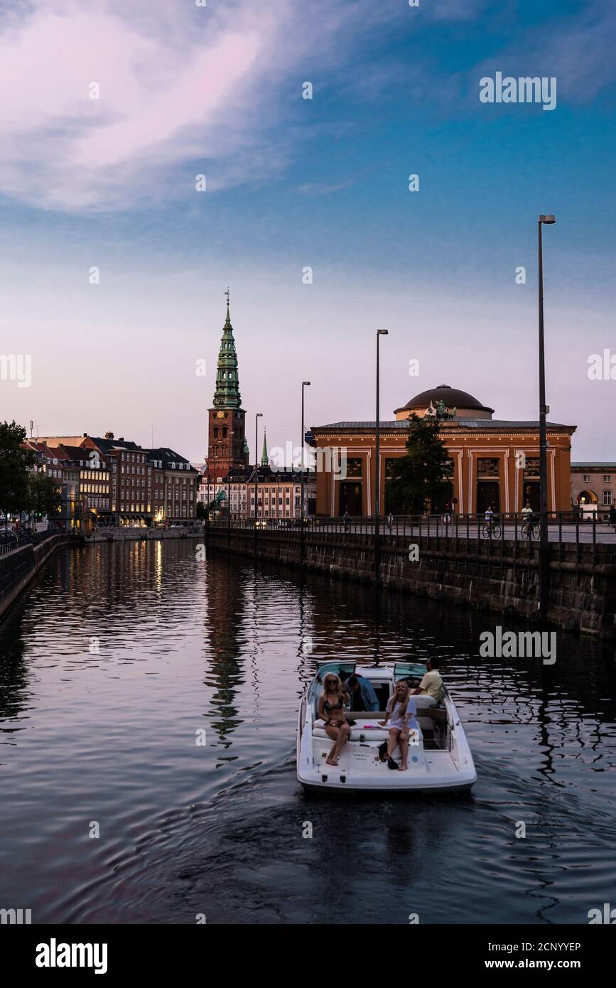 Copenhagen, Denmark - August 26, 2019: People on board a yacht in swimsuits sailing at sunset along Frederiksholms canal in Copenhagen, Denmark Stock Photo