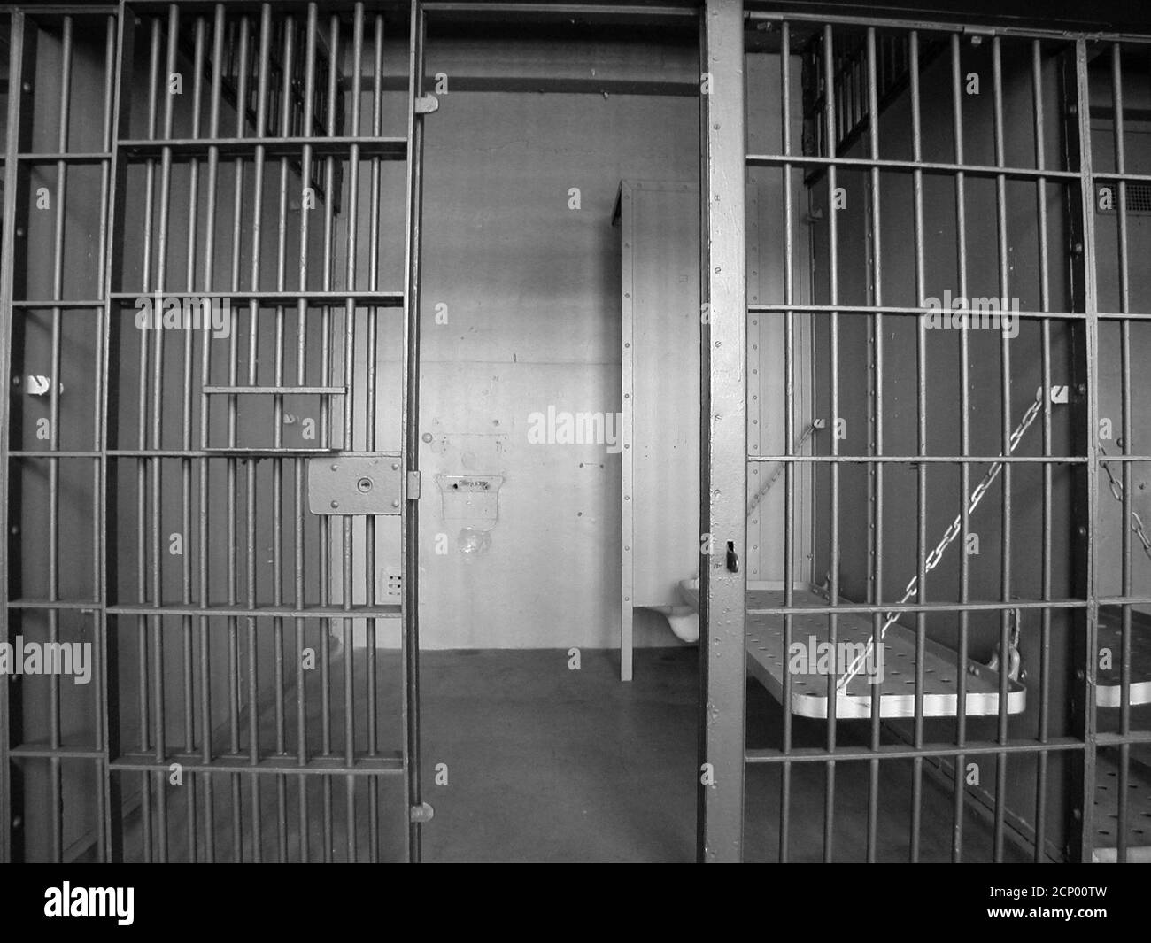 Black and white view inside empty jail cell block in an closed rundown government owned facility. Stock Photo