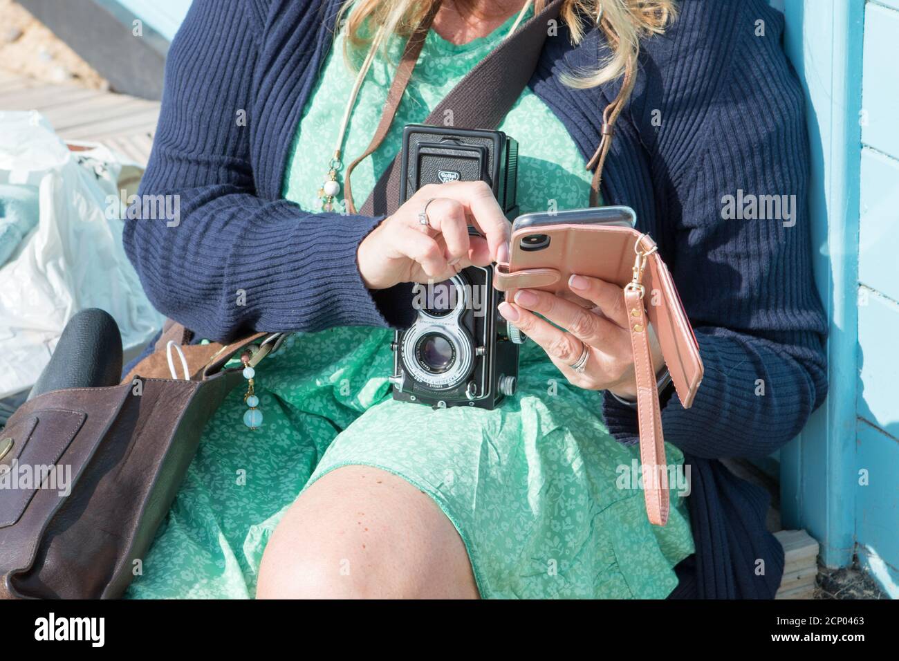 A woman uses her digital phone with a retro vintage Rolleiflex twin ...