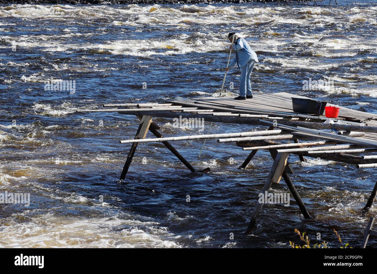 Kukkola, Sweden - August 24, 2020: A man is traditional fishing for lavaret (whitefish) in the Kukkola rapids in the Tornio river. Stock Photo