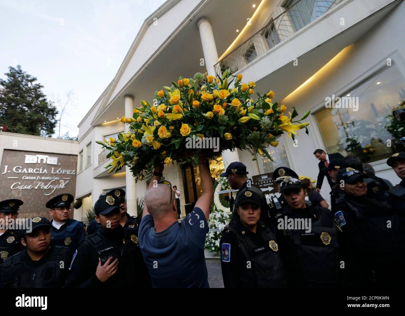 A man carries a flower wreath while passing through a line of police officers outside the funeral home where the body of Colombian Nobel Prize laureate Gabriel Garcia Marquez was taken to, in Mexico City April 17, 2014. Garcia Marquez, the Colombian author whose beguiling stories of love and longing brought Latin America to life for millions of readers and put magical realism on the literary map, died on Thursday. He was 87. Fans will pay their last respects to him in the Palace of Fine Arts in Mexico City on Monday and he will be cremated in a private ceremony. REUTERS/Henry Romero (MEXICO  - Stock Photo