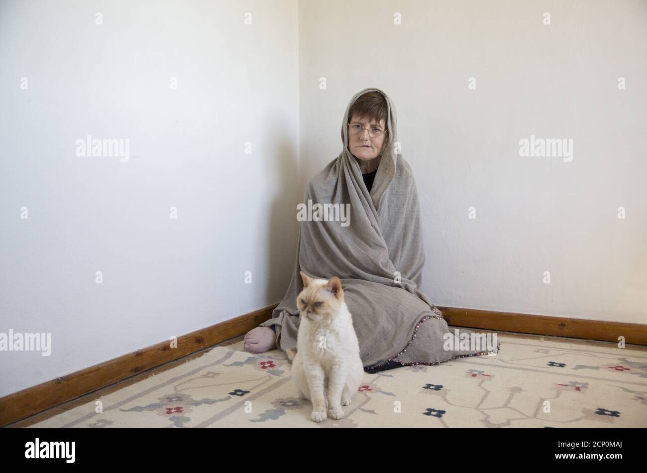 Sister Rachel Denton sits with a cat in St Cuthbert's Hermitage in Lincolnshire, north east Britain April 27, 2015. Denton, a Catholic hermit, rises early to tend to her vegetable garden, feed her cats and pray. But the former Carmelite nun, who in 2006 pledged to live the rest of her life in solitude, has another chore - to update her Twitter account and check Facebook. 'The myth you often face as a hermit is that you should have a beard and live in a cave. None of which is me,' says the ex-teacher. For the modern-day hermit, she says social media is vital: 'tweets are rare, but precious,' sh Stock Photo