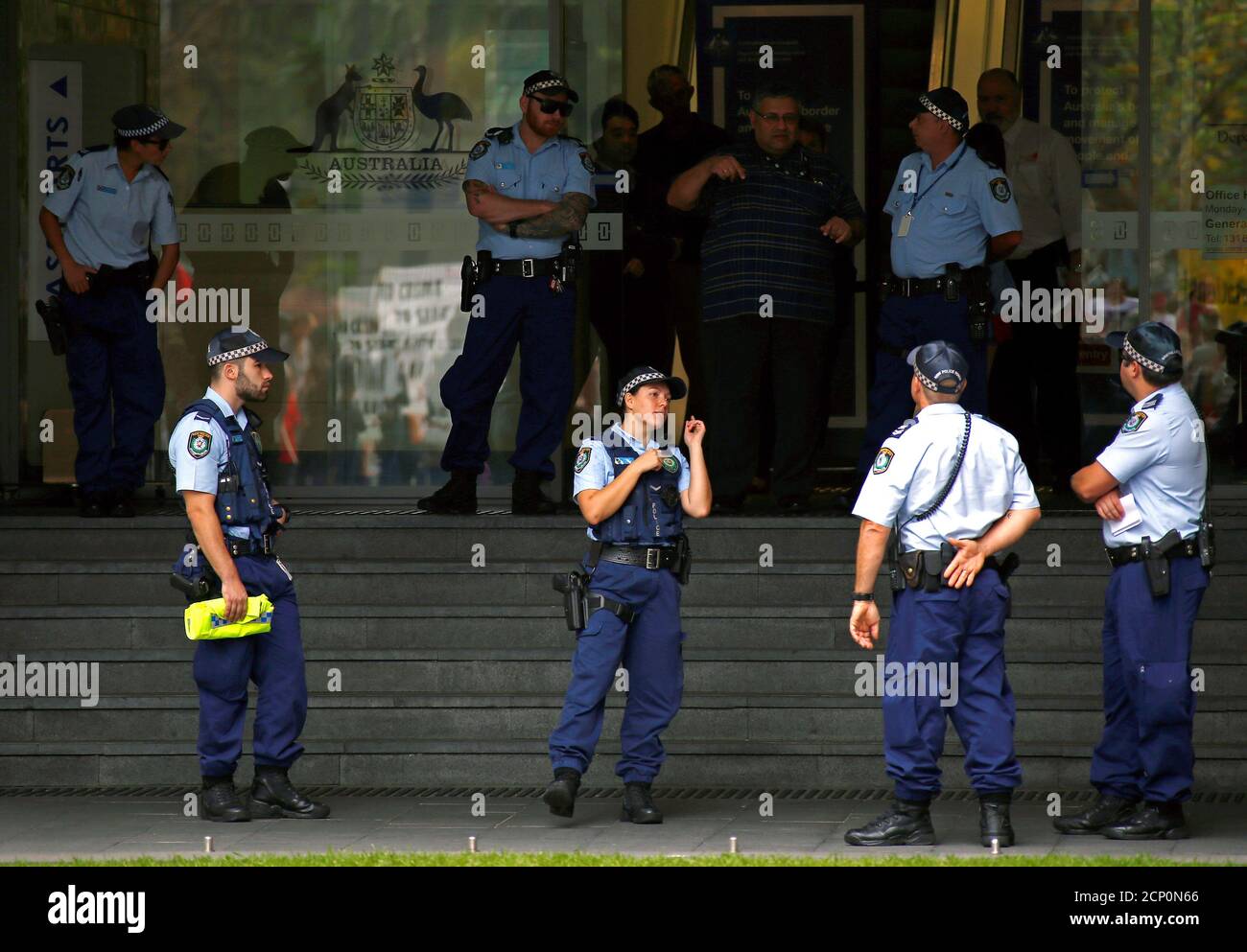 stand guard outside the offices of the Australian Government Department of Immigration and Border Protection as protesters from the Refugee Action Coalition hold a demonstration nearby in Sydney, Australia, April 29,