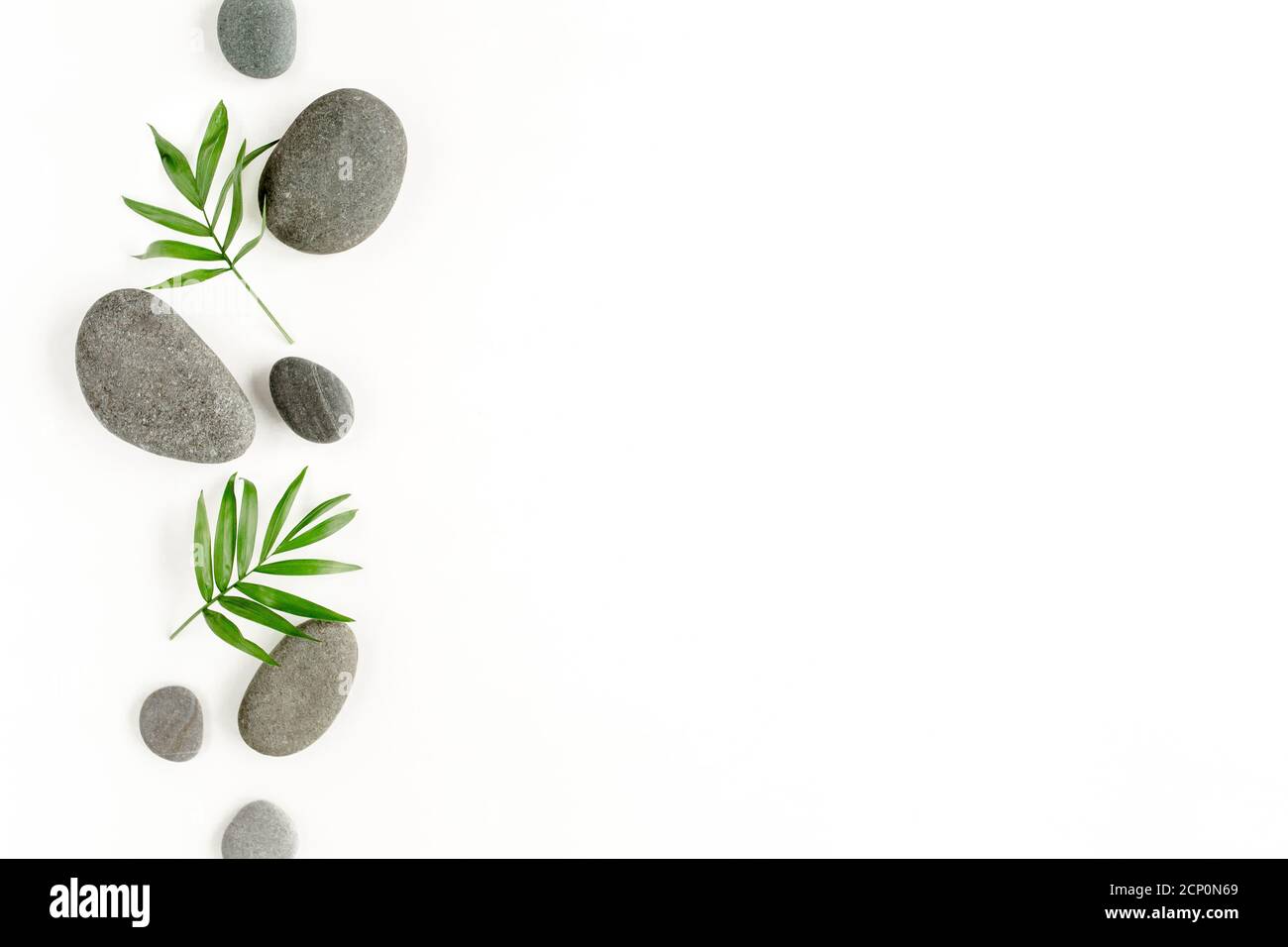 Spa stones, palm leaves, candle and zen like grey stones on white ...