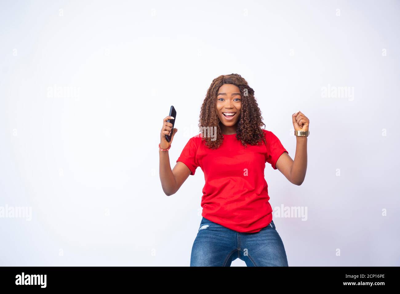 young black lady holding her phone feeling excited and celebrating Stock Photo