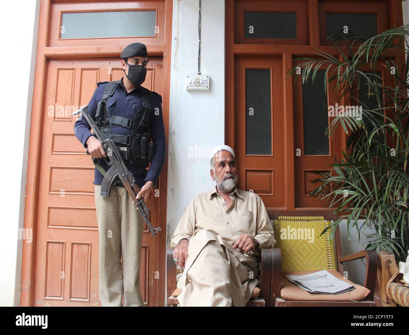 Swat Valley shopkeeper Abdur Rahim speaks with a Reuters correspondent as one of police bodyguards stands guard over him at his home in Mingora, Pakistan November 22, 2016. REUTERS/Hazrat Ali Bacha Stock Photo