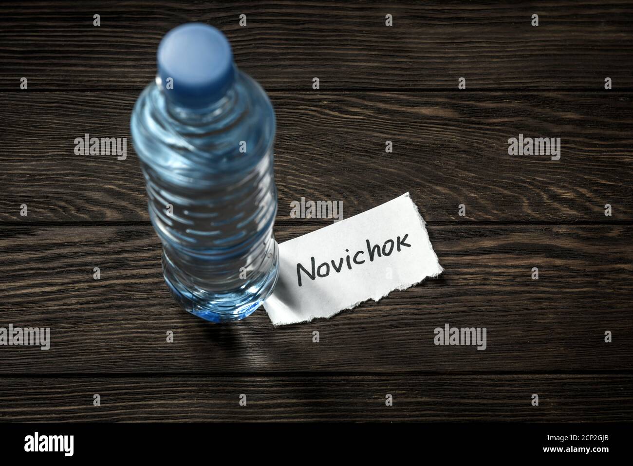 Bottle of water and note Novichok on wooden table. Novichok is agent poison, deadly nerve venom. Concept of Navalny incident, intelligence service, se Stock Photo