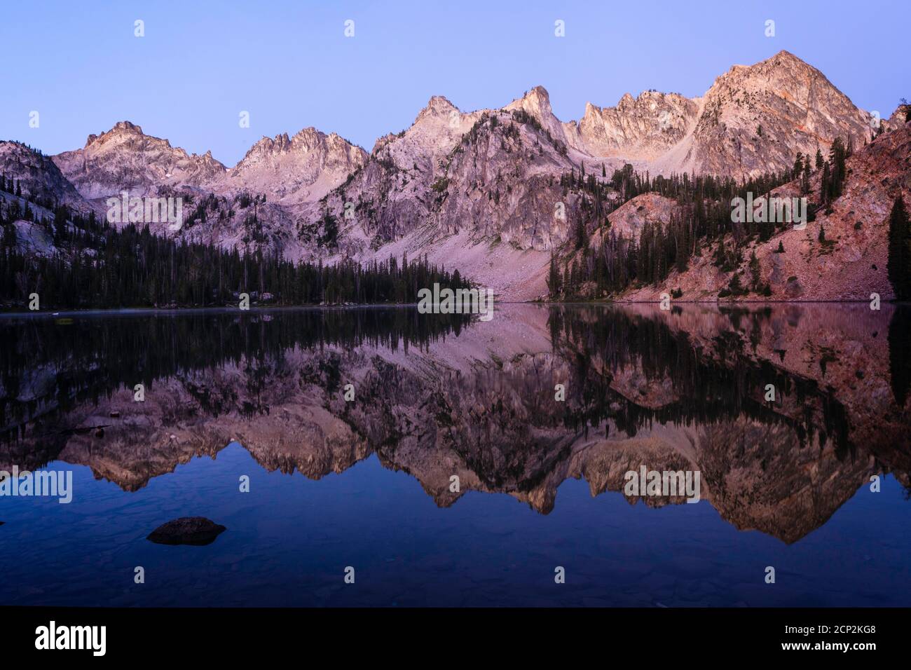 Alice Lake reflects the surrounding peaks at twilight, Sawtooth Wilderness, Idaho, USA. Stock Photo